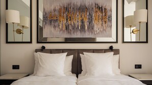 A double bed with white bedding, two bedside tables, a wall-mounted painting, and two wall-mounted lamps. - Beau-Rivage Nyon (Nyon)