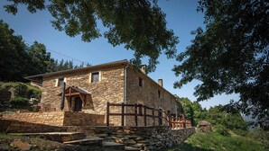 A stone building with a wooden porch and a stone staircase leading up to the entrance. - Casa Liñeiras Solpor (A Pontenova)