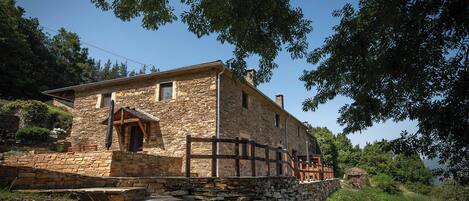 A stone building with a wooden porch and a stone staircase leading up to the entrance.