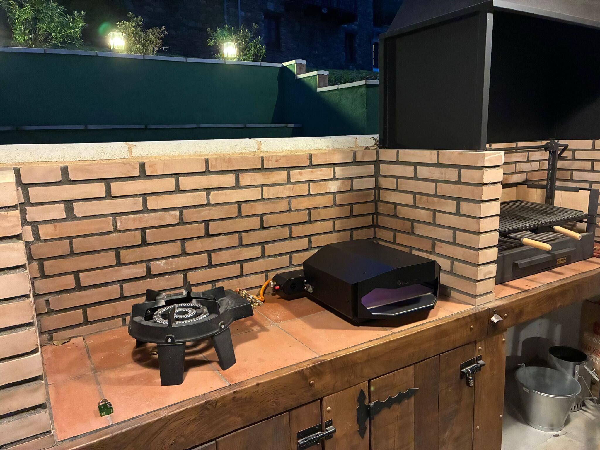 A brick-built outdoor kitchen with a gas stove, a pizza oven, and a grill.