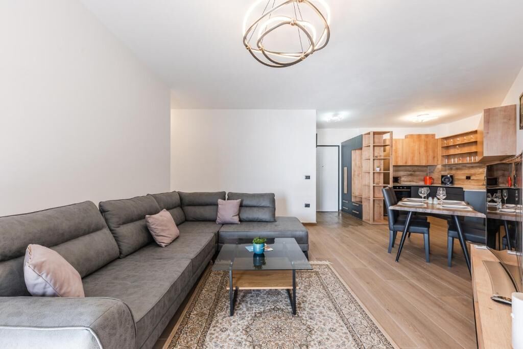 A modern living room with a grey sectional sofa, a coffee table, and a dining area with a wooden table and chairs.