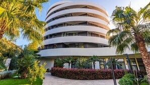 A multi-story building with a circular design, surrounded by palm trees and well-maintained gardens. - Hill Side Suite 1 by PS (Durrës)