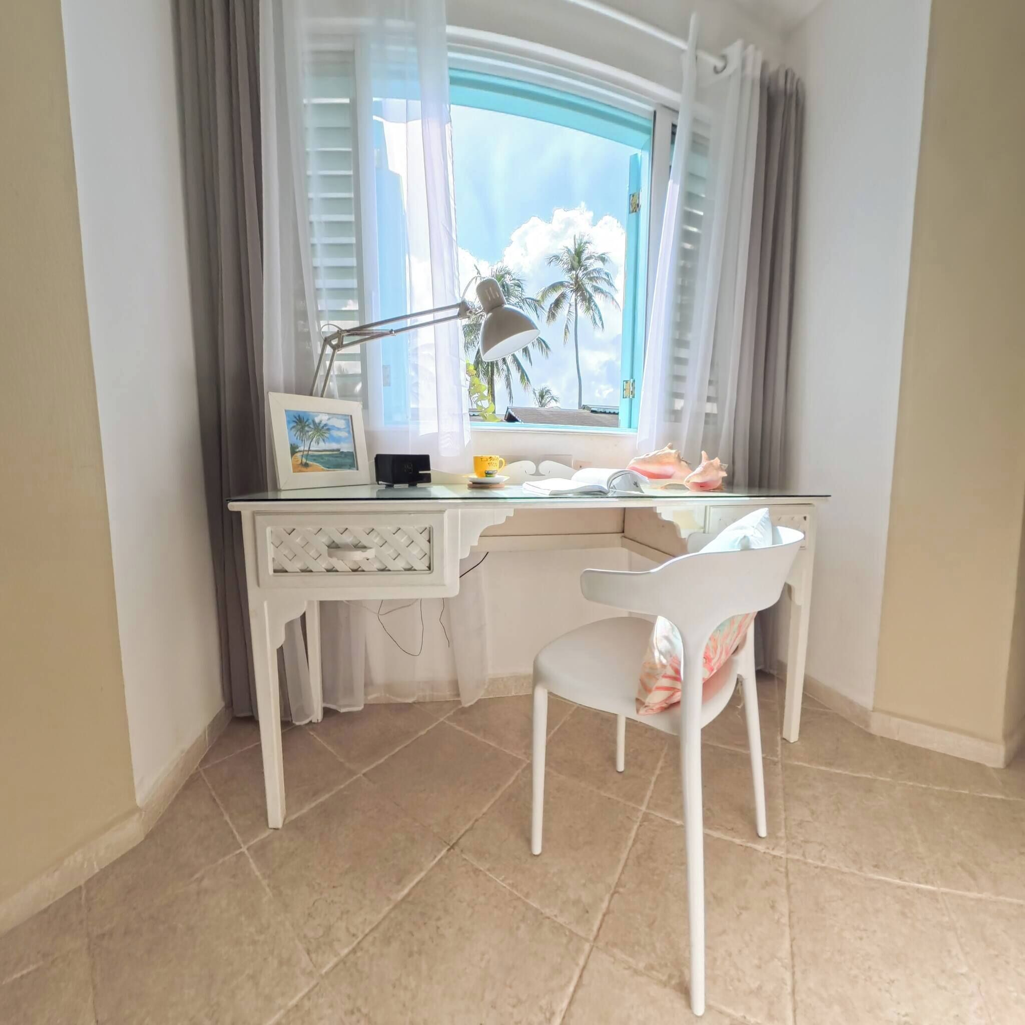 Une pièce d’angle comprenant un bureau, une chaise et une fenêtre avec des rideaux.