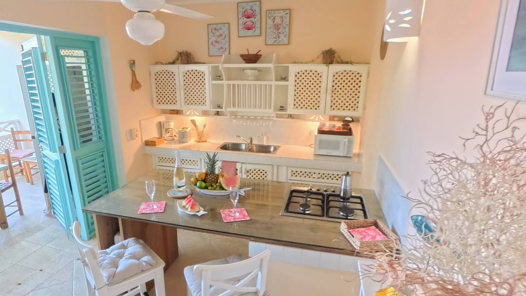Une cuisine dotée d’un îlot central, de meubles blancs, d’un four à micro-ondes et d’une cuisinière à gaz.