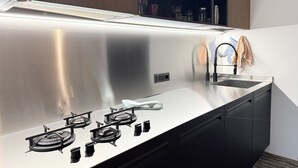 Una cocina moderna con encimera de acero inoxidable, estufa integrada y un fregadero.