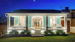 A two-story house with a covered porch, large windows, and a well-maintained lawn. - Veles Dos – Seafront Villa with Private Pool and Stunning Views (Sa Marina - Barcarés - Manresa)