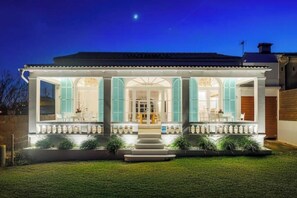 A two-story house with a covered porch, large windows, and a well-maintained lawn. - Veles Dos – Seafront Villa with Private Pool and Stunning Views (Sa Marina - Barcarés - Manresa)