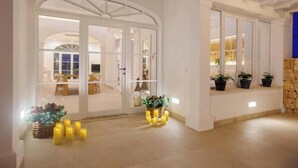 A modern interior with a glass door entrance, a stone wall, and a seating area with potted plants. - Veles Dos – Seafront Villa with Private Pool and Stunning Views (Sa Marina - Barcarés - Manresa)