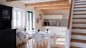 A modern kitchen with wooden beams, white cabinets, and a dining area with a white table and chairs. - Remark Studios: Historic and modern Apartment (Burgwedel)