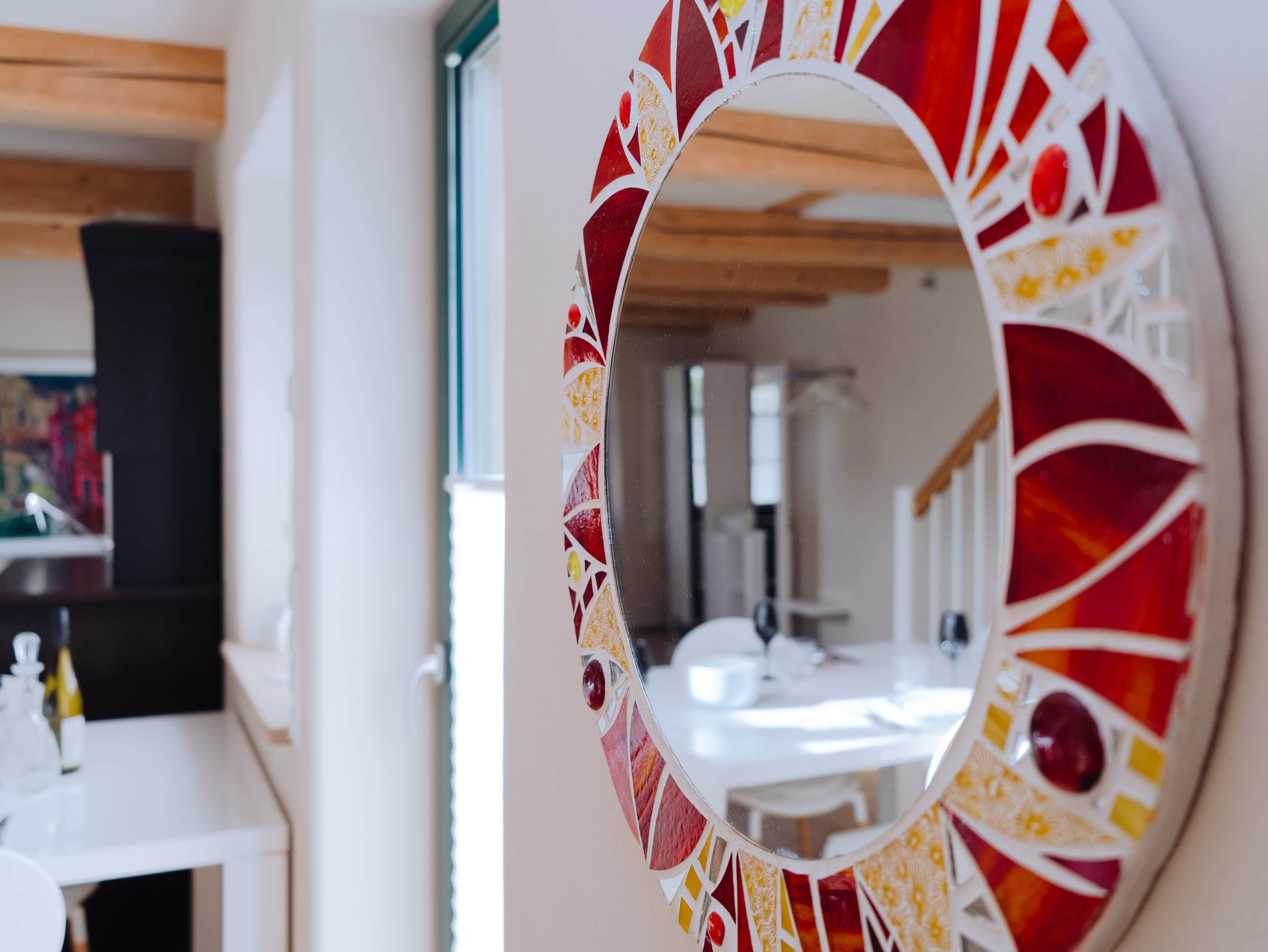 A mirror with a decorative frame in a room with a white sink and cabinets.