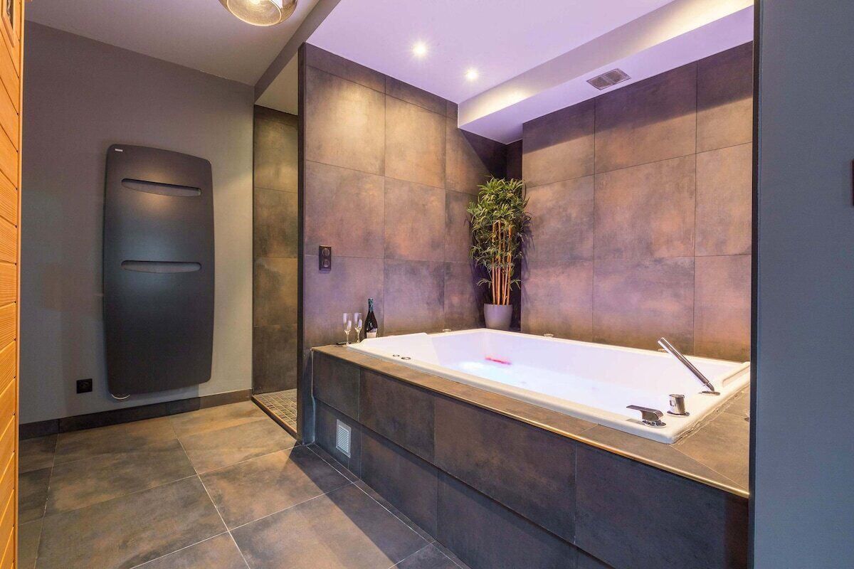 Un baño moderno con una bañera grande, un calentador de pared y una planta en maceta.