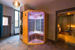 Un sauna d’angle doté d’une paroi en verre, de lambris en bois et d’un luminaire au plafond.