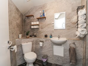 Ein Badezimmer mit Toilette, Waschbecken, Handtuchhalter und Ablagen für Toilettenartikel.