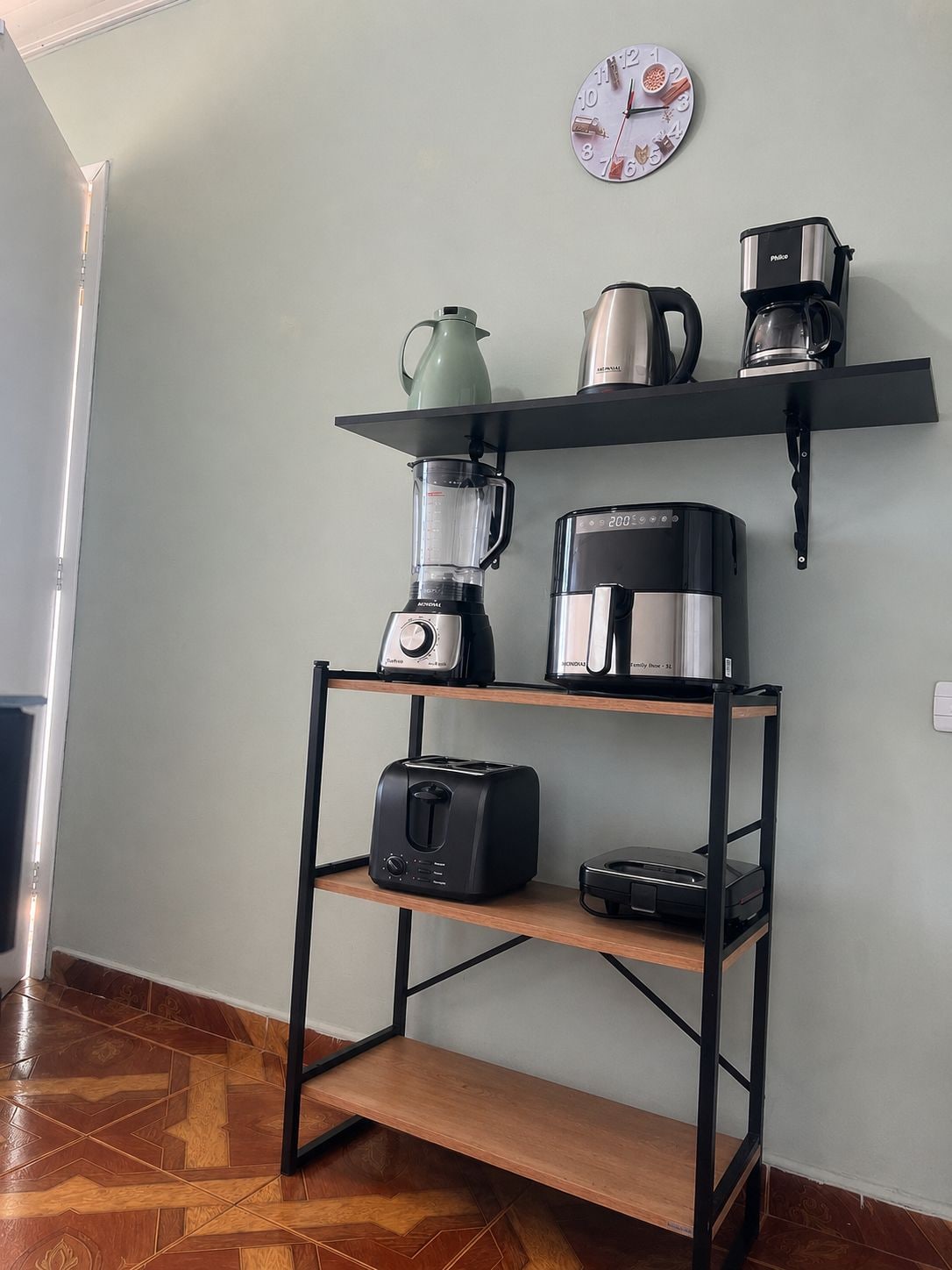 A kitchenette with a coffee maker, a blender, a kettle, and a toaster on a shelf.