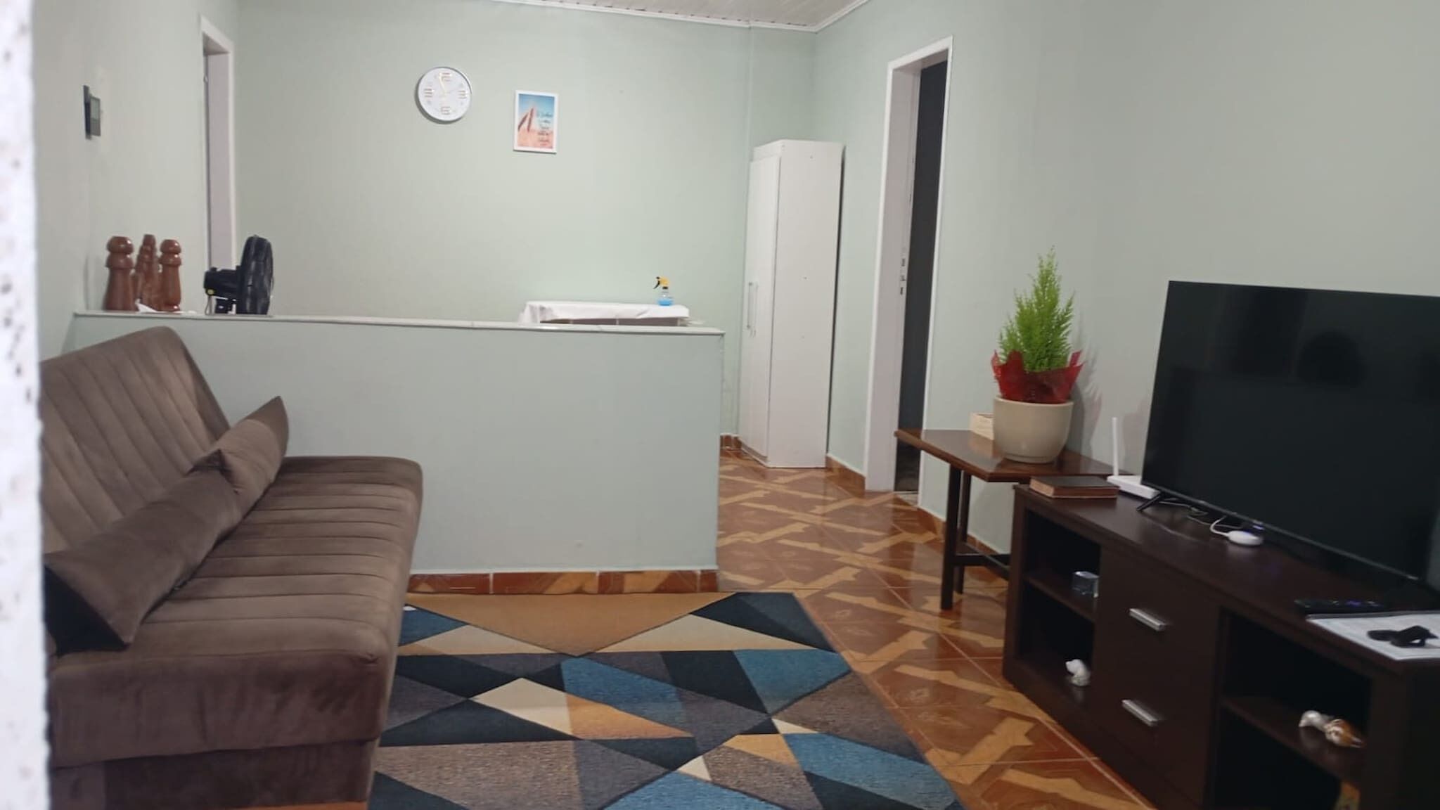 A living room with a sofa, a TV, a coffee table, and a patterned rug.