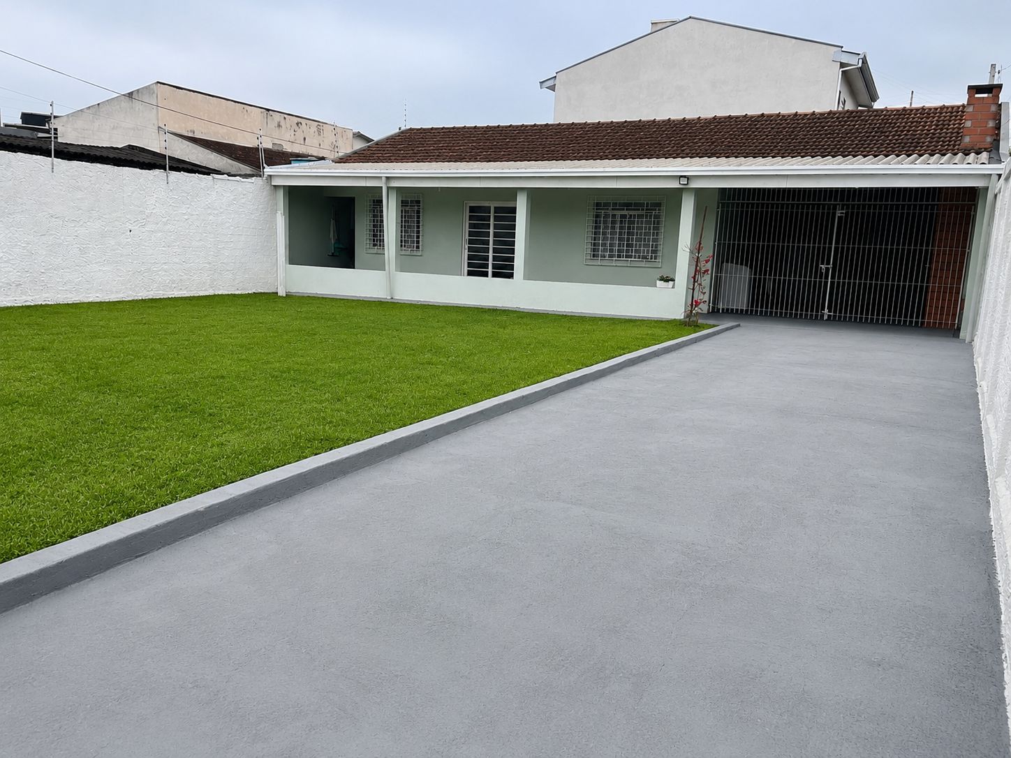 A residential property with a paved driveway, a green lawn, and a gated entrance.