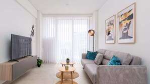 Een moderne woonkamer met een bank, een televisie en kunst aan de muur.