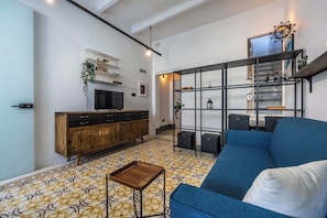 Een moderne woonkamer met een blauwe bank, een houten kast en een vloer met een patroon.