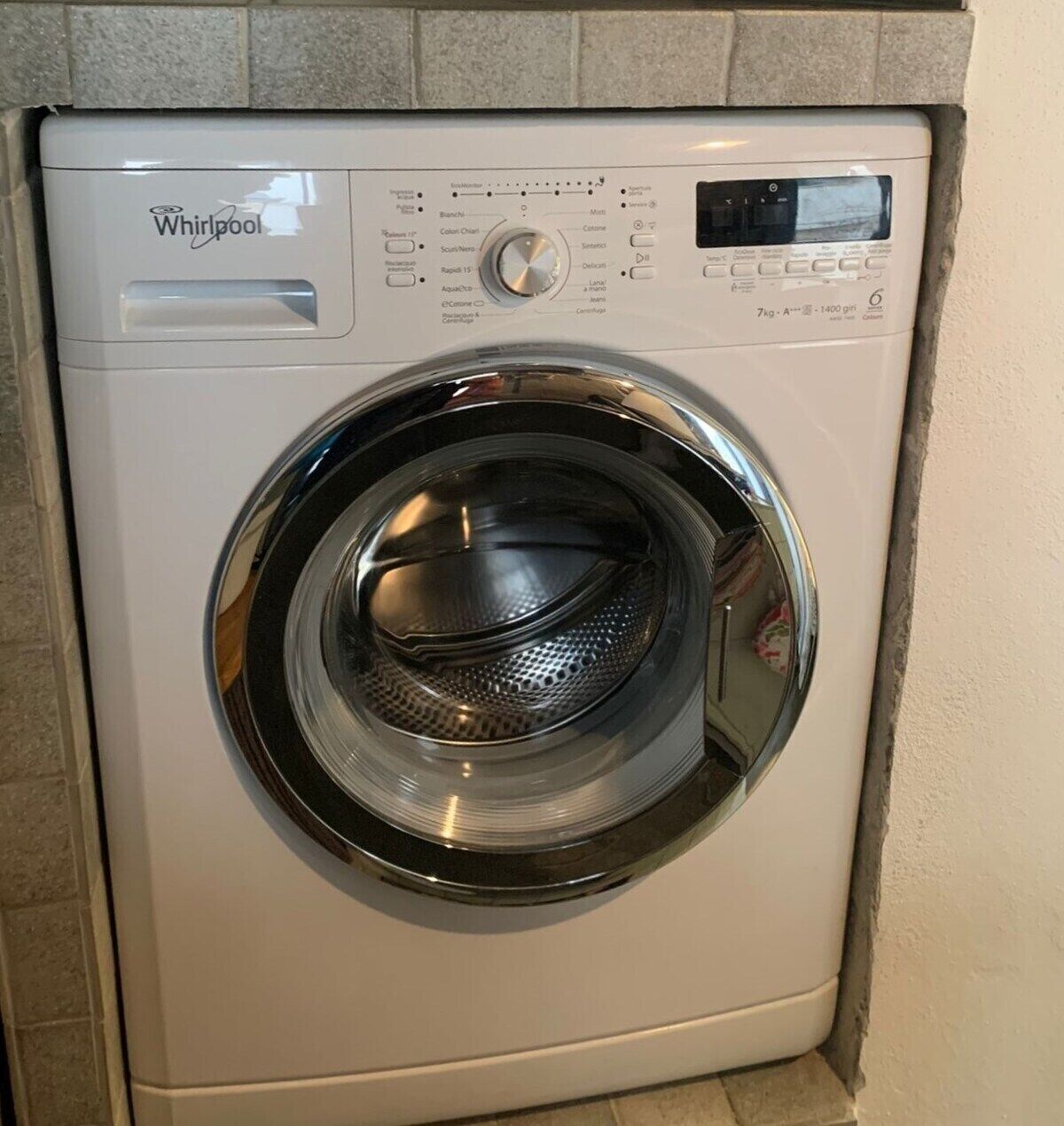 Una lavadora Whirlpool de carga frontal con pantalla digital, panel de control y puerta de acero inoxidable.