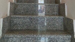 Un escalier avec des marches en granit menant à un palier.