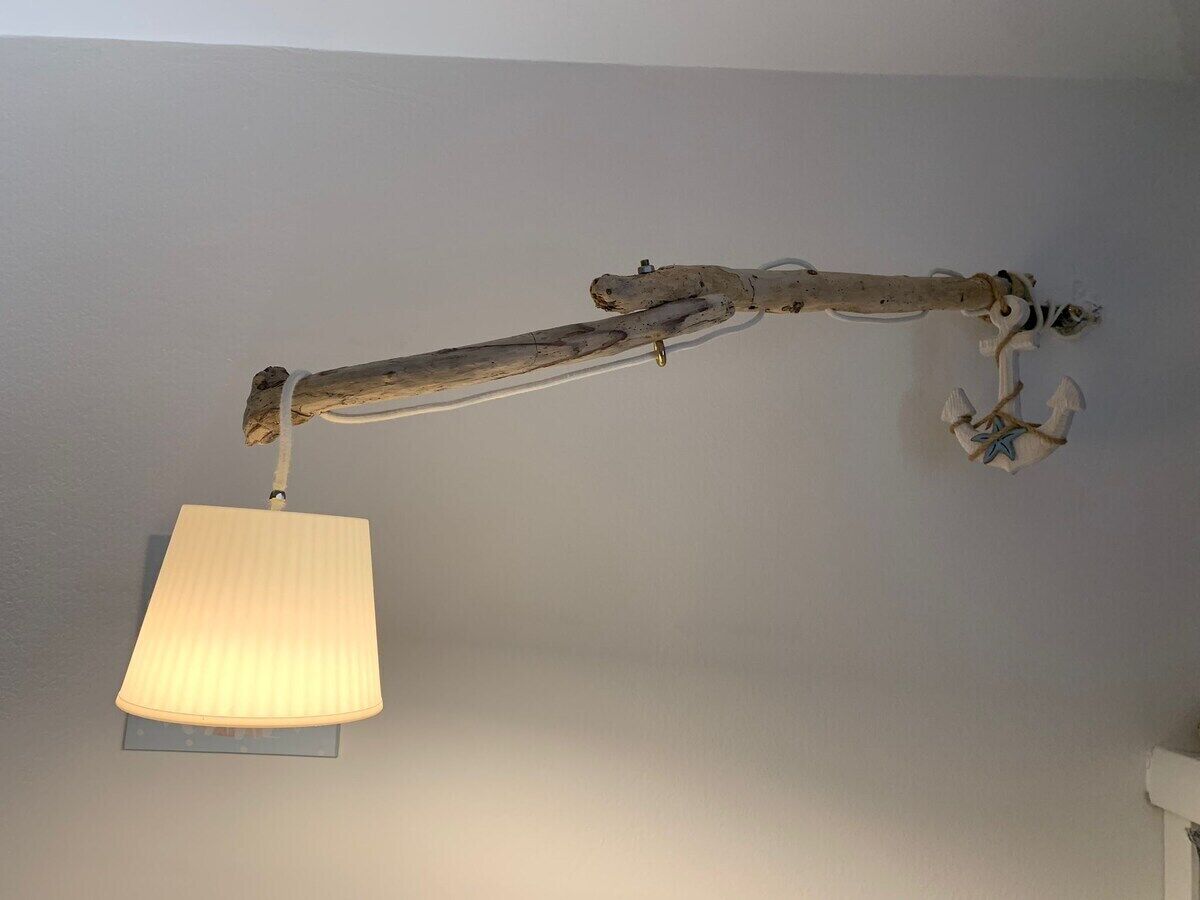 Een plafondlamp met een witte lampenkap en een rustieke houten arm.