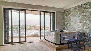 A modern room with a sliding glass door leading to a balcony, a spa tub, and a small table. - Sliema 3BDR Flat with Seaview and Jacuzzi (Tas-Sliema)