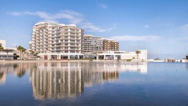 A modern hotel with multiple balconies, a waterfront view, and a reflection in the water. - Shoreline Residence Brand NEW 1 BDR Apartment (Kalkara)