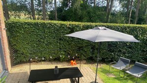 An outdoor patio with a table and chairs, a barbecue grill, and a hedge in the background. - Self-catering cottage with year-round heated indoor swimming pool (Ramillies)