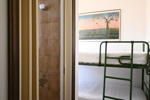 Une pièce avec un lit superposé, un espace douche et un tableau accroché au mur.