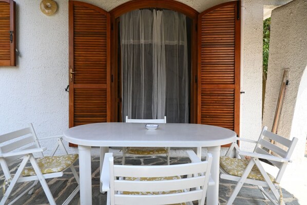 Une table ronde avec quatre chaises, une porte en bois avec des volets et un mur blanc.