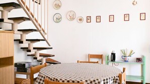 A room with a staircase, a round table with a checkered tablecloth, and a wall with framed pictures. - M444 - Marcelli, comfortable four-room apartment with outdoor patio (Marcelli)
