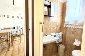 Une pièce comprenant une table à manger, des chaises, un évier et des toilettes.