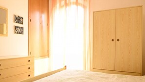 A bedroom with a bed, wooden wardrobe, and a dresser. - M444 - Marcelli, comfortable four-room apartment with outdoor patio (Marcelli)