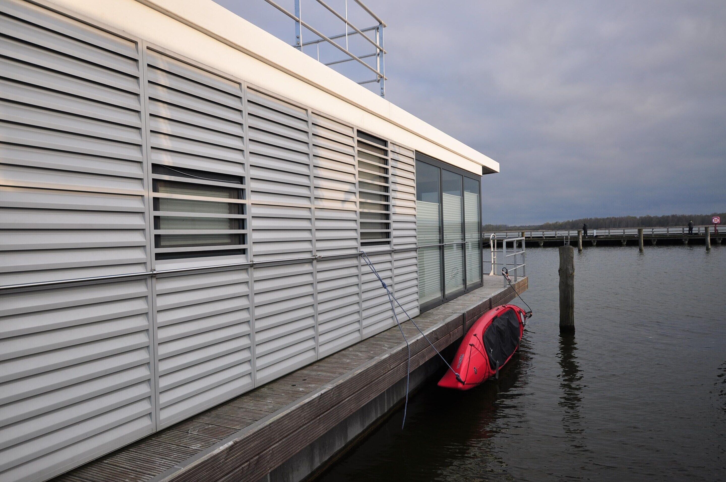 Un edificio moderno con revestimiento horizontal y un muelle que se adentra en el agua.