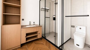 Un baño moderno con tocador de madera, cabina de ducha de vidrio y inodoro blanco.