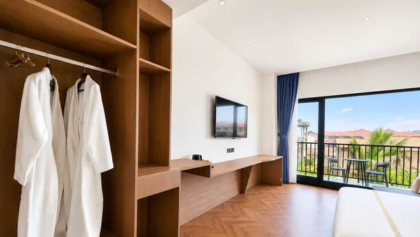 Habitación de hotel con un armario grande, una cama, televisión y balcón con vistas.