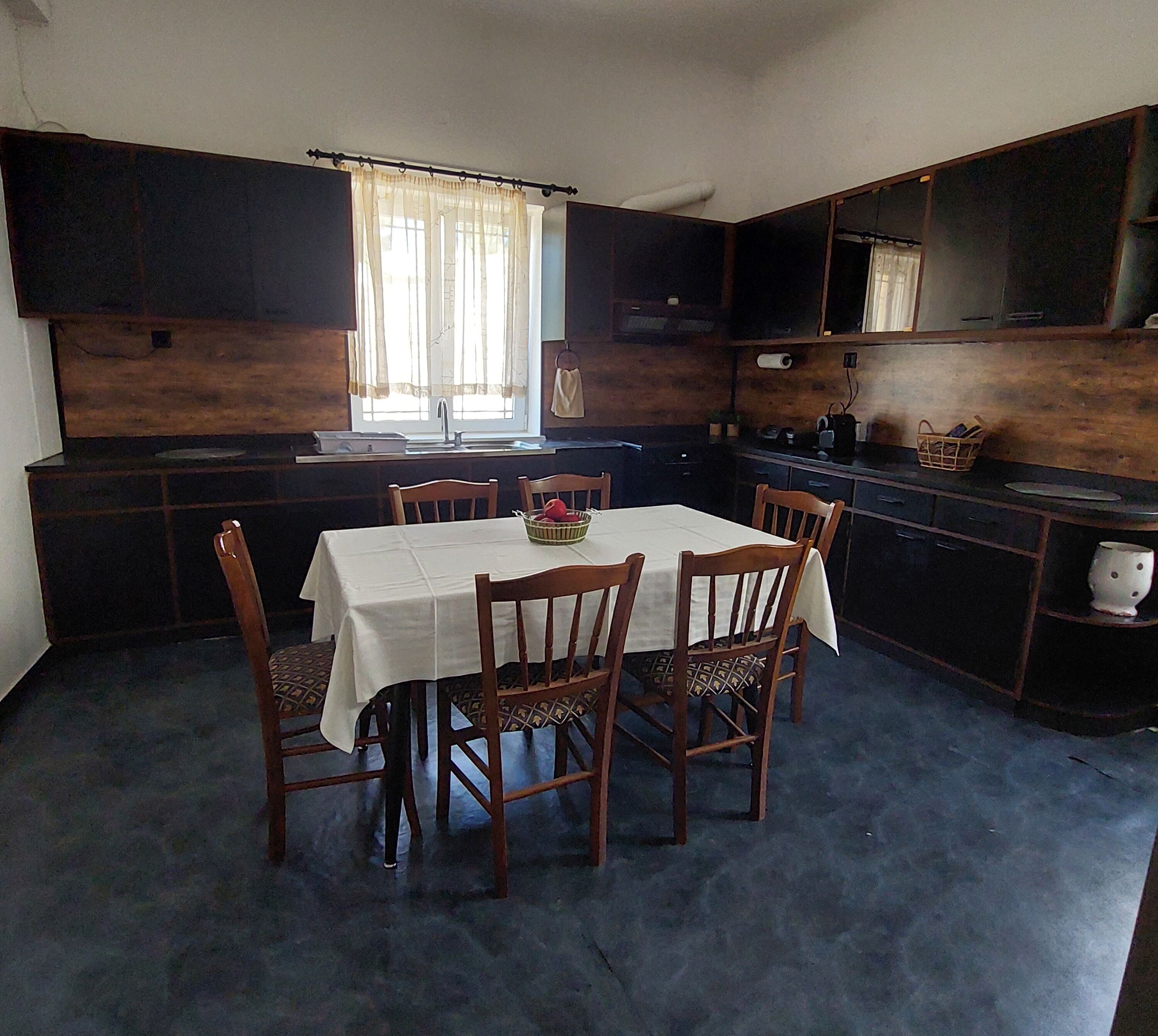 Une cuisine de taille réduite comprenant une table à manger, des chaises et une fenêtre avec des rideaux.