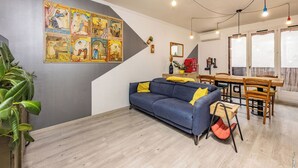 Un salon moderne avec un mur gris, un canapé bleu et un coin repas comprenant une table et des chaises en bois.