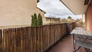Une terrasse en bois avec une table et des chaises, une clôture en bois et un bâtiment en arrière-plan.