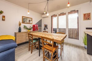 A dining area with a wooden table and chairs, a sofa, and a small cabinet.