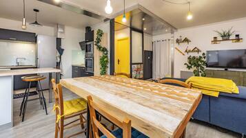 A modern kitchen with a wooden dining table, bar stools, and a built-in oven.