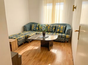 A room with a sectional sofa, a coffee table, and a door with a brass handle. - Comfy 3BR Near Belvedere Palace (Vienna)
