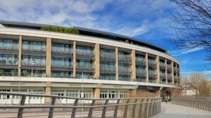 A modern building with multiple floors, large windows, and a curved facade.