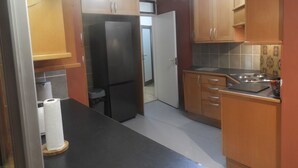 Una cucina compatta con mobili in legno, un piano di lavoro nero e un frigorifero in acciaio inossidabile.