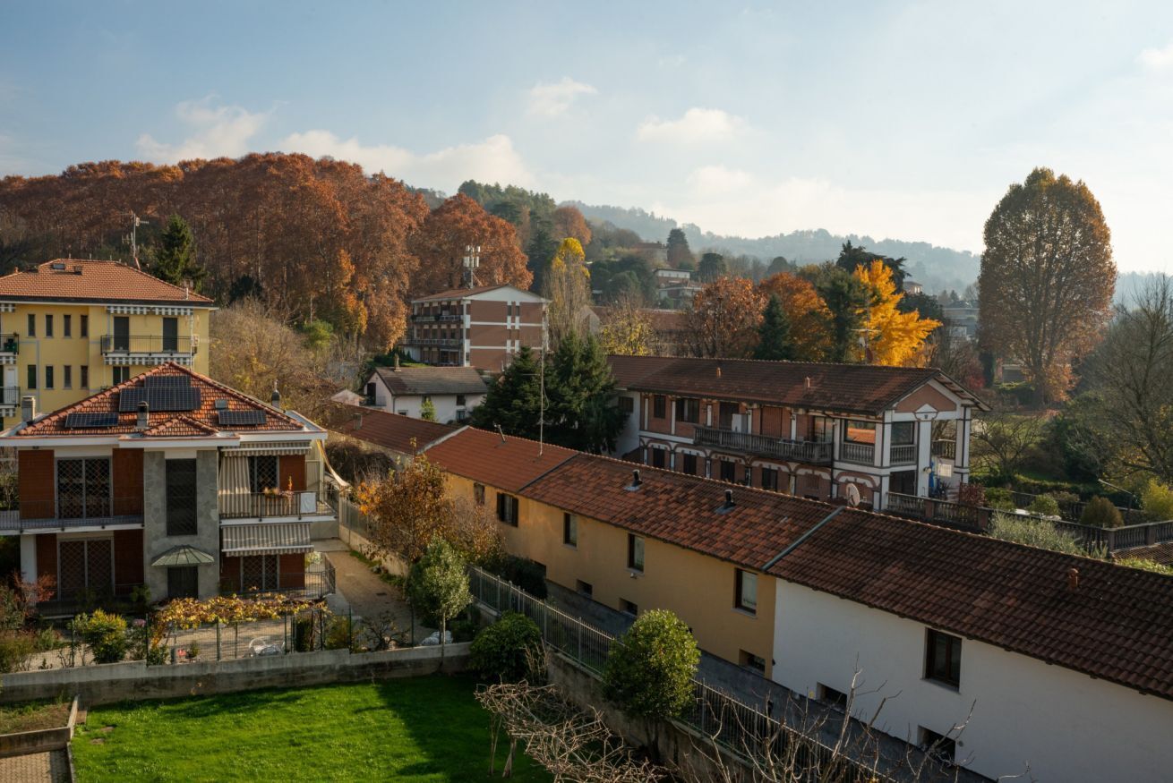 A residential area with multi-story buildings, a green lawn, and trees with autumn foliage.
