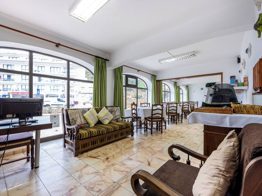 Un salón espacioso con sofá, sillones, televisor y mesa de comedor.