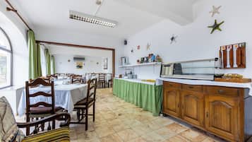 Un coin repas avec des chaises et des tables en bois, un comptoir de cuisine et des étoiles de mer décoratives accrochées au mur.