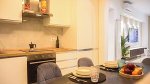 Une cuisine moderne dotée d’un plan de travail en marbre, d’un four encastré et d’un coin repas avec une table dressée pour deux personnes.