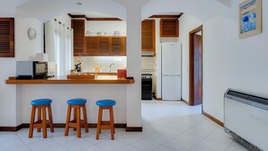 Eine Küche mit Holzschränken, einem weißen Kühlschrank und einer kleinen Kücheninsel mit Sitzgelegenheiten.