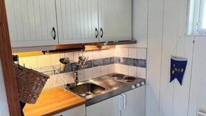 A compact kitchen with white cabinets, a stainless steel sink, and a wooden countertop. - Room-archipelago Cottage is Utö (Uto)